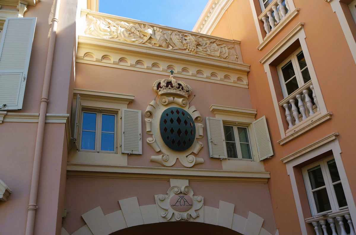 Pink Monaco building with the princely Grimaldi coat of arms above an archway