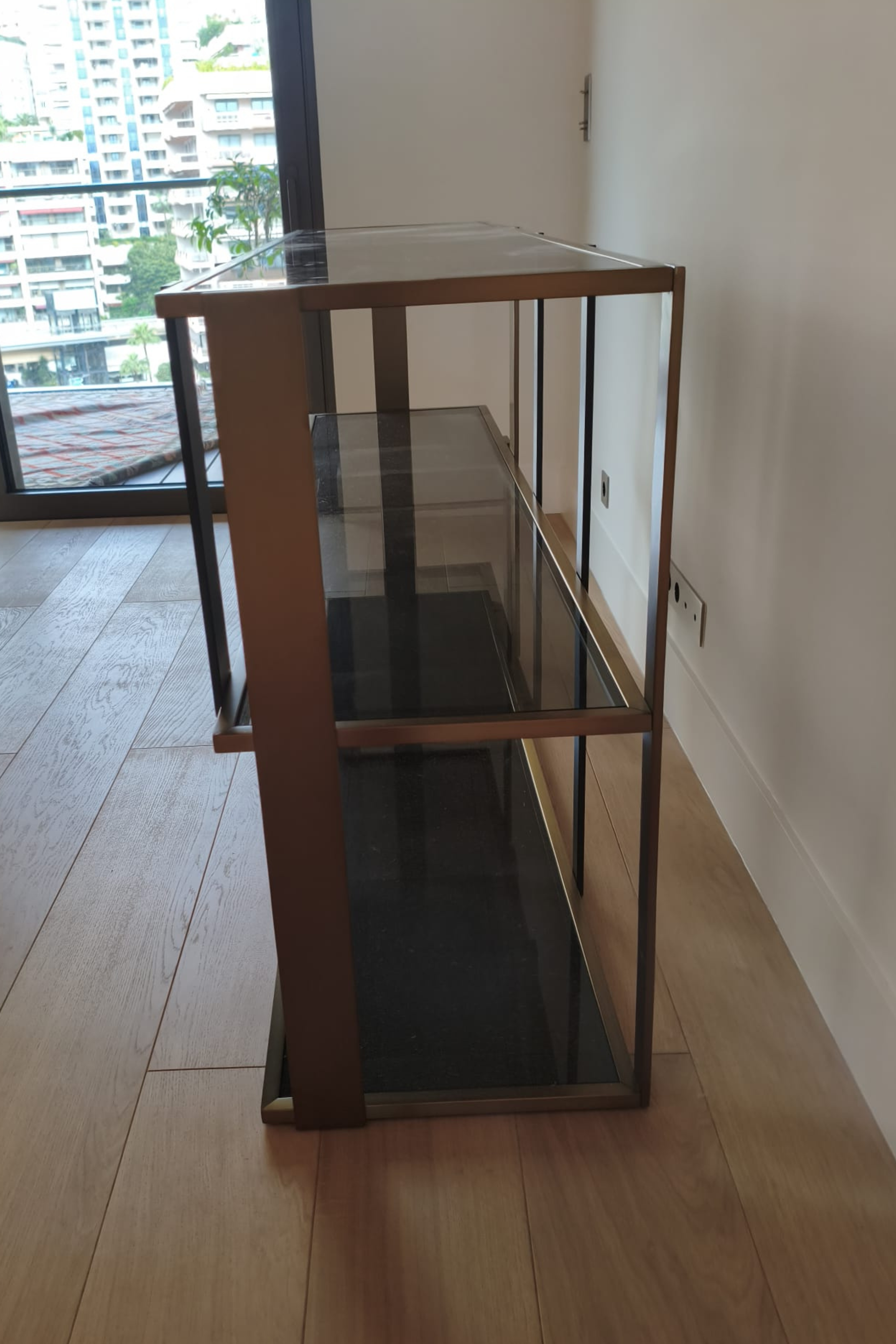 Eichholtz Clio console cabinet with brushed brass finish and smoked glass doors, showcasing a sleek modern design.