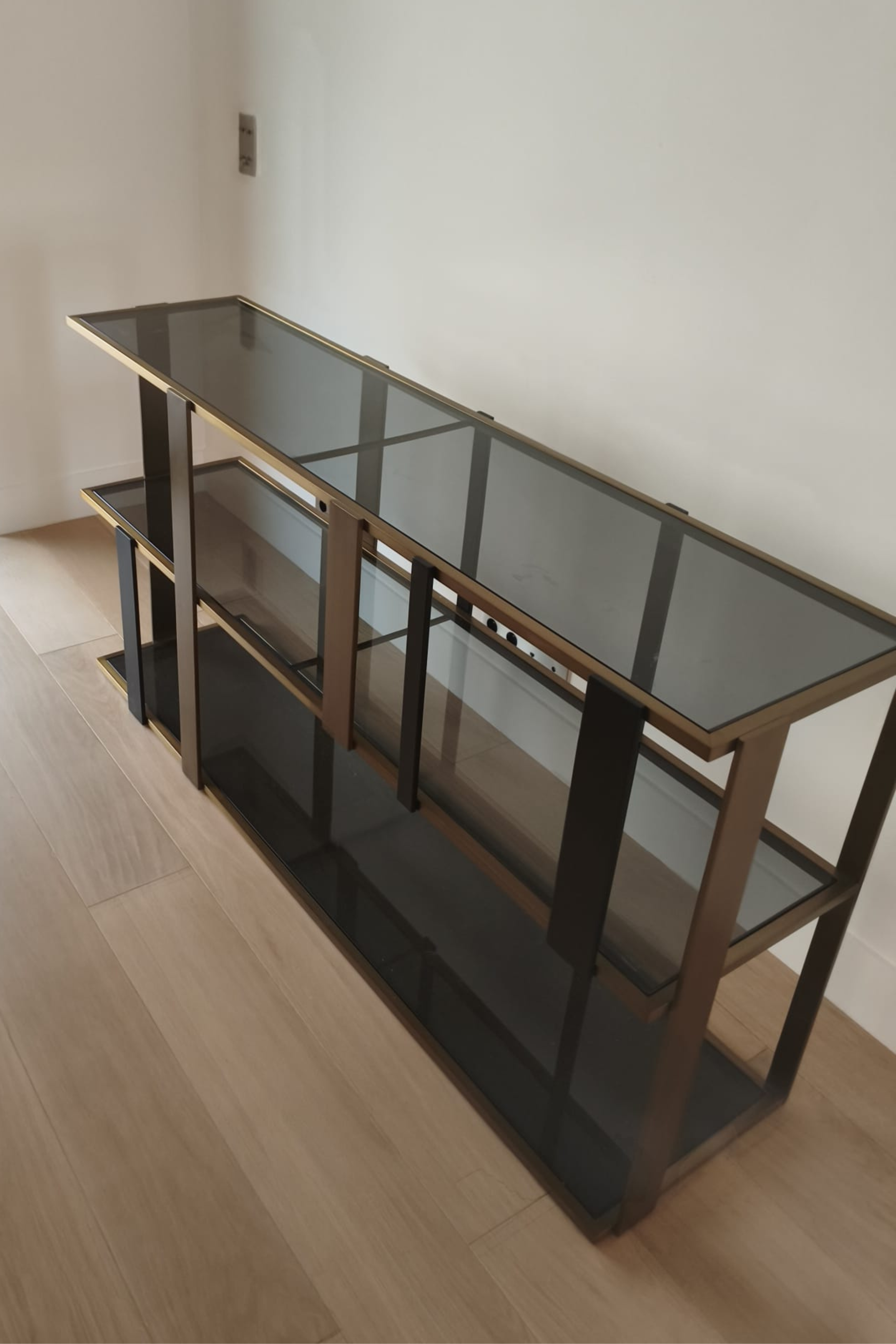 Eichholtz Clio console cabinet with brushed brass finish and smoked glass doors, showcasing elegant storage and modern design.