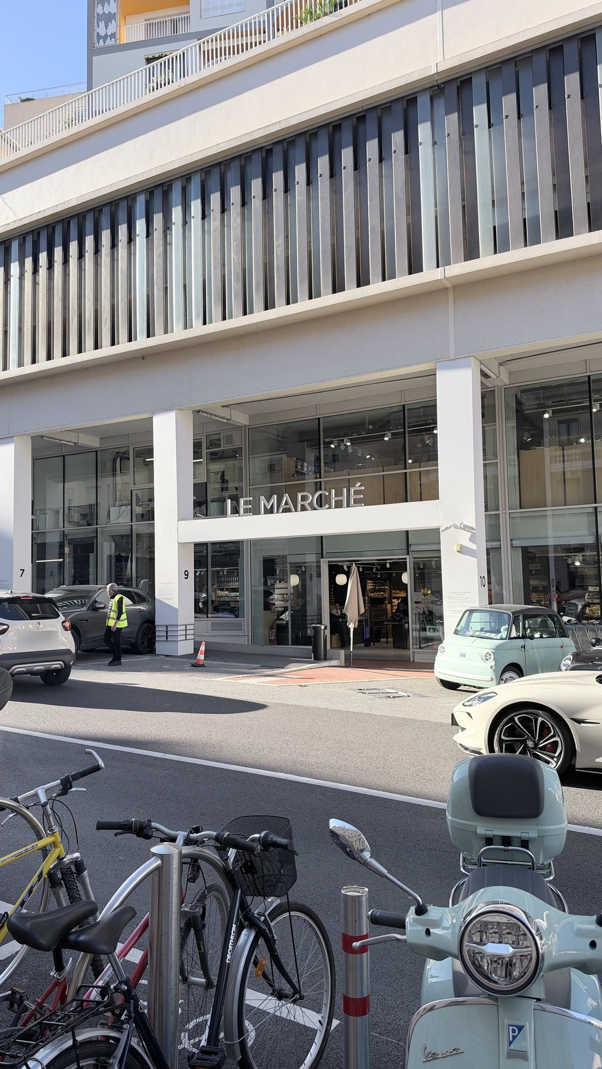 Supermarket entrance on a Monaco street, with parked scooters and bicycles in front