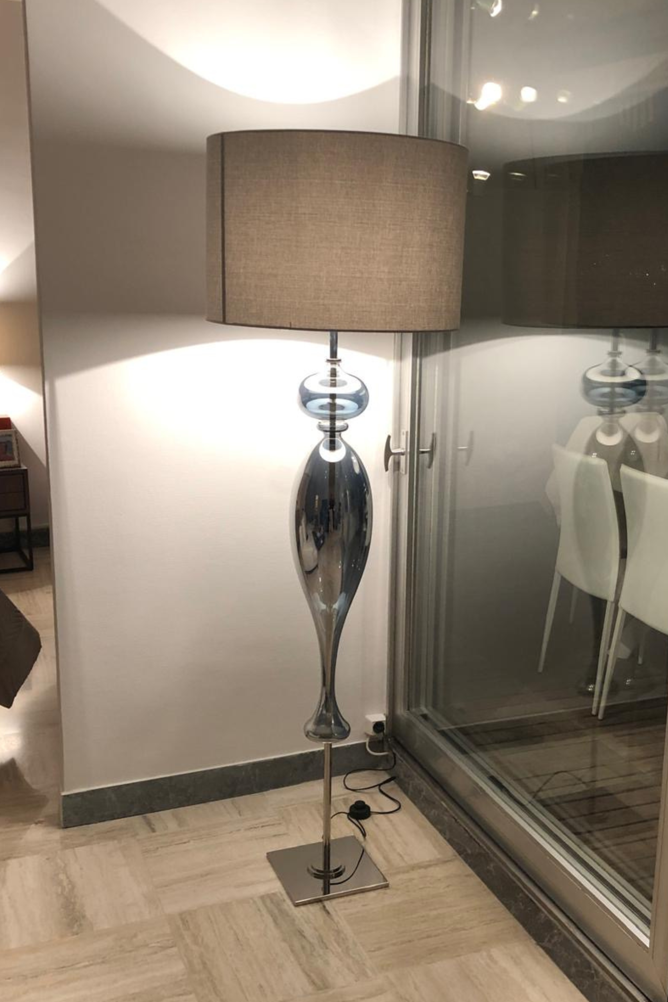 Contemporary smoked glass floor lamp with chrome base by Melanie Gouchon, featuring a sleek, modern design and elegant lighting.