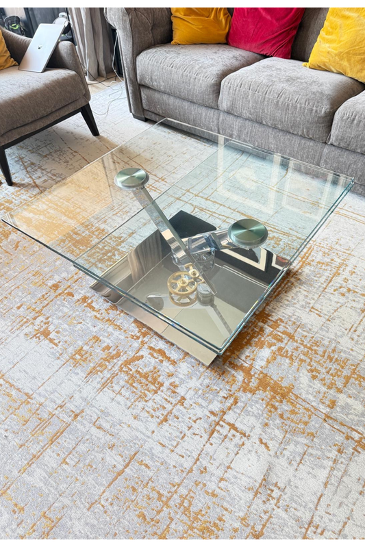 Glass and metal coffee table with mechanical detail by Serpil Barrington-Serle, showcasing modern design and intricate craftsmanship.