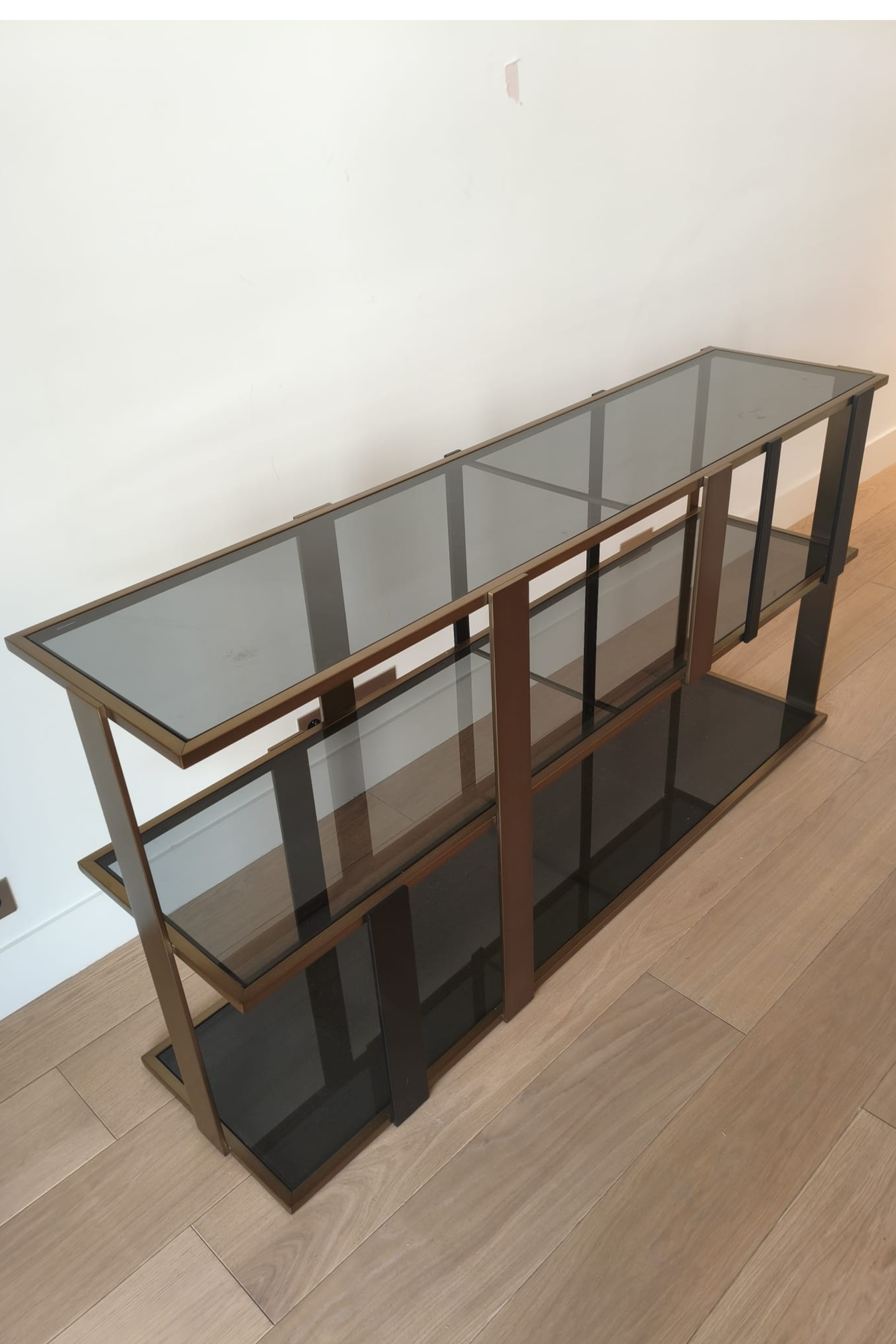 Eichholtz Clio console cabinet with brushed brass frame and smoked glass doors, showcasing a sleek, modern design.